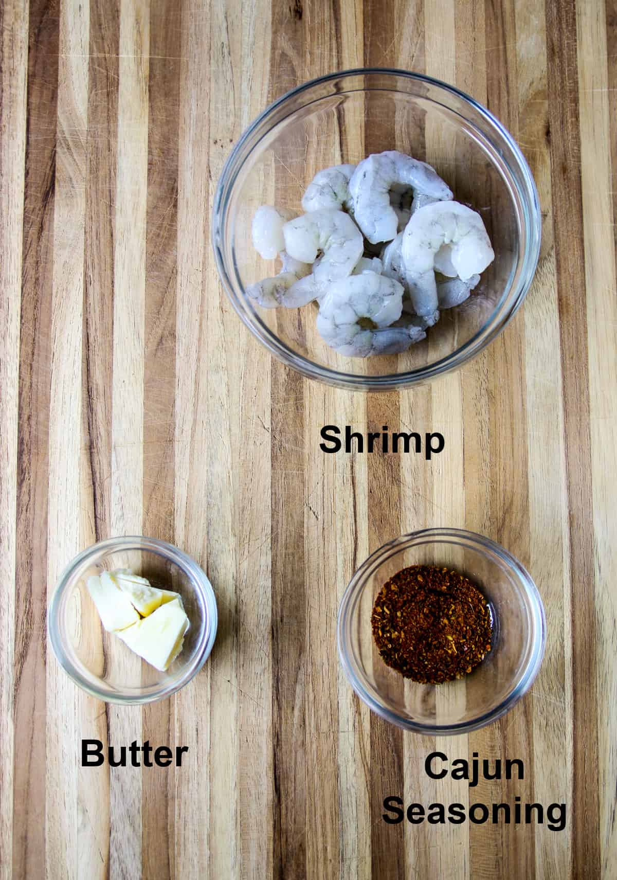 The ingredients for making the shrimp, in glass bowls on a wood cutting board.