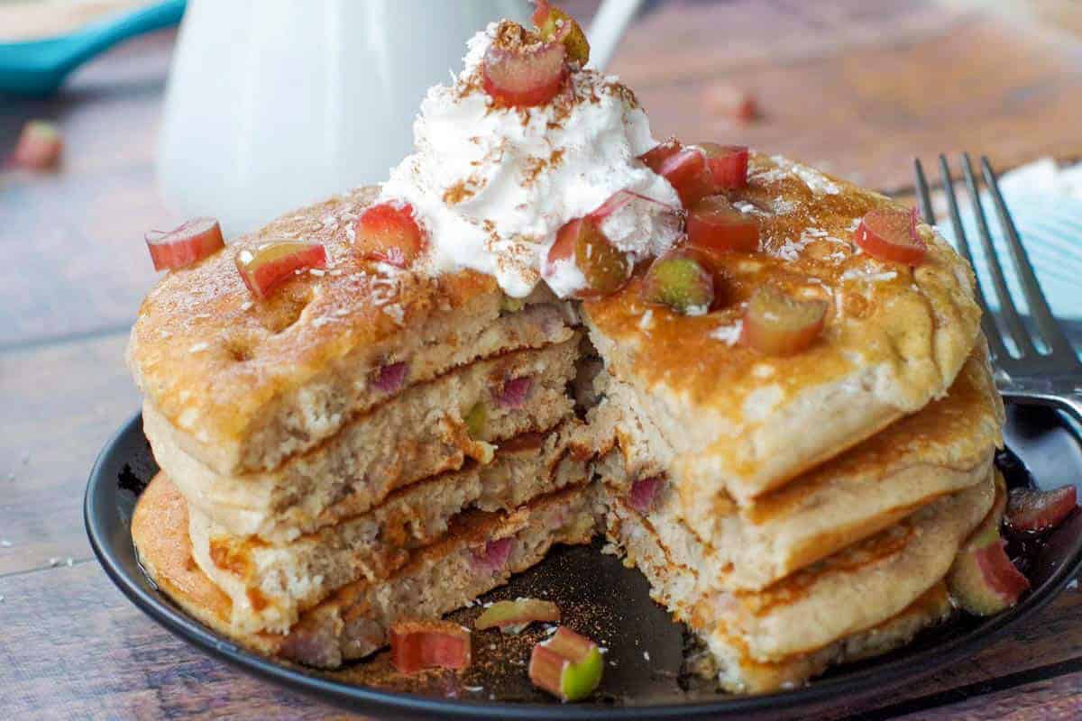A stack of rhubarb pancakes topped with whipped cream.