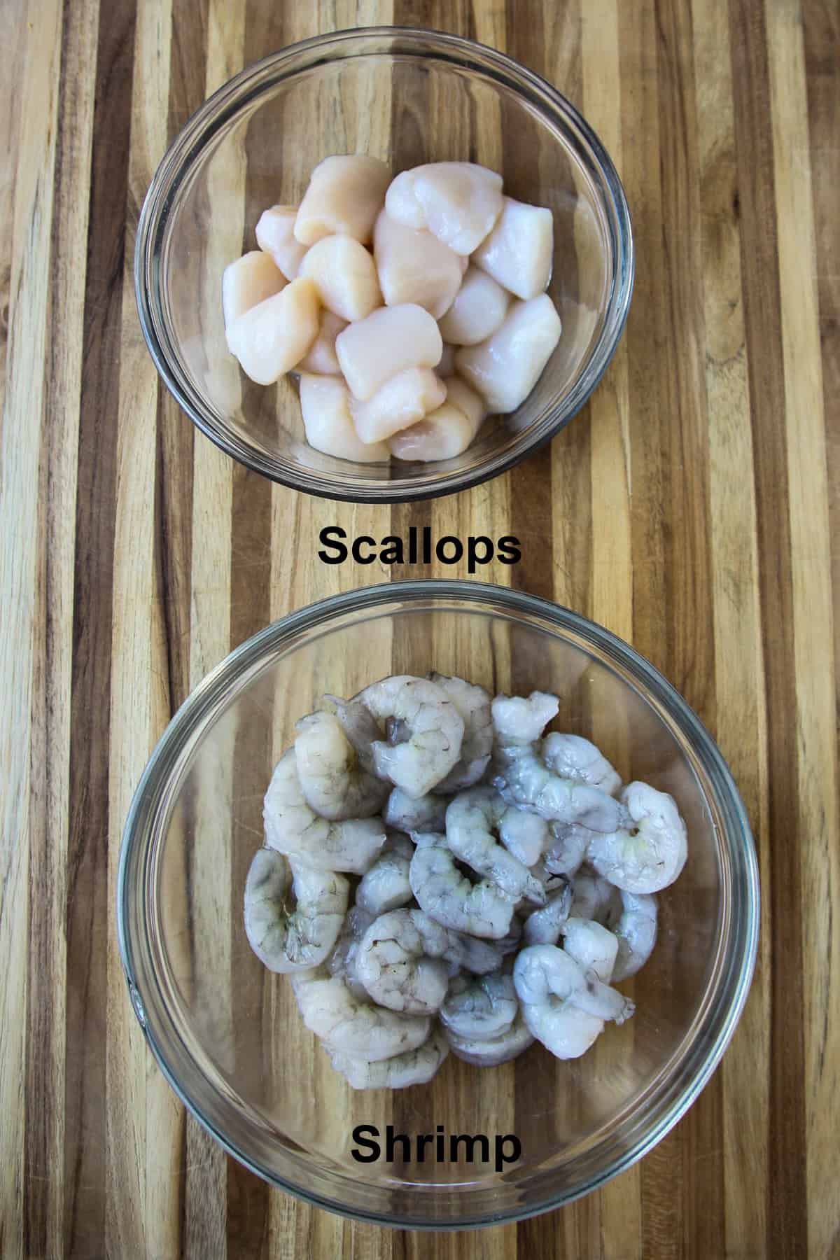 Raw shrimp and scallops in glass bowls.
