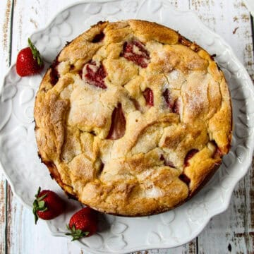 A French strawberry cake, garnished with strawberries, on a cake plate.