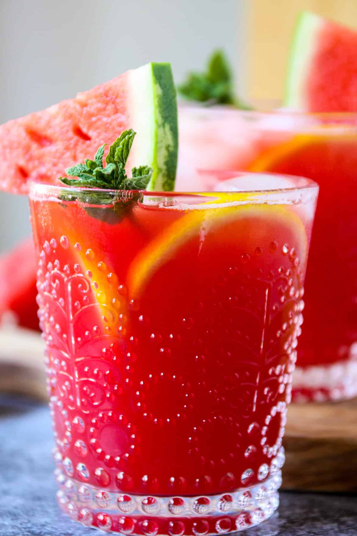 A vodka watermelon cocktail in a clear patterned glass.
