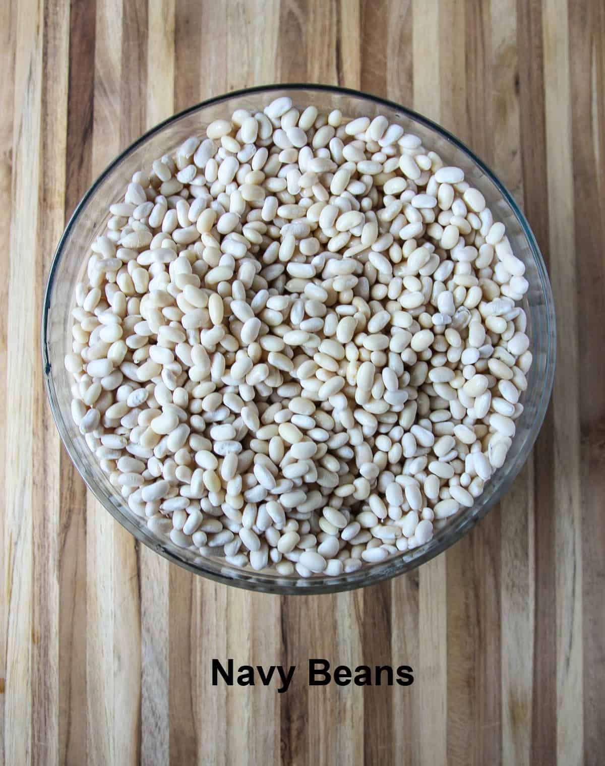 Dried navy beans in a glass bowl.