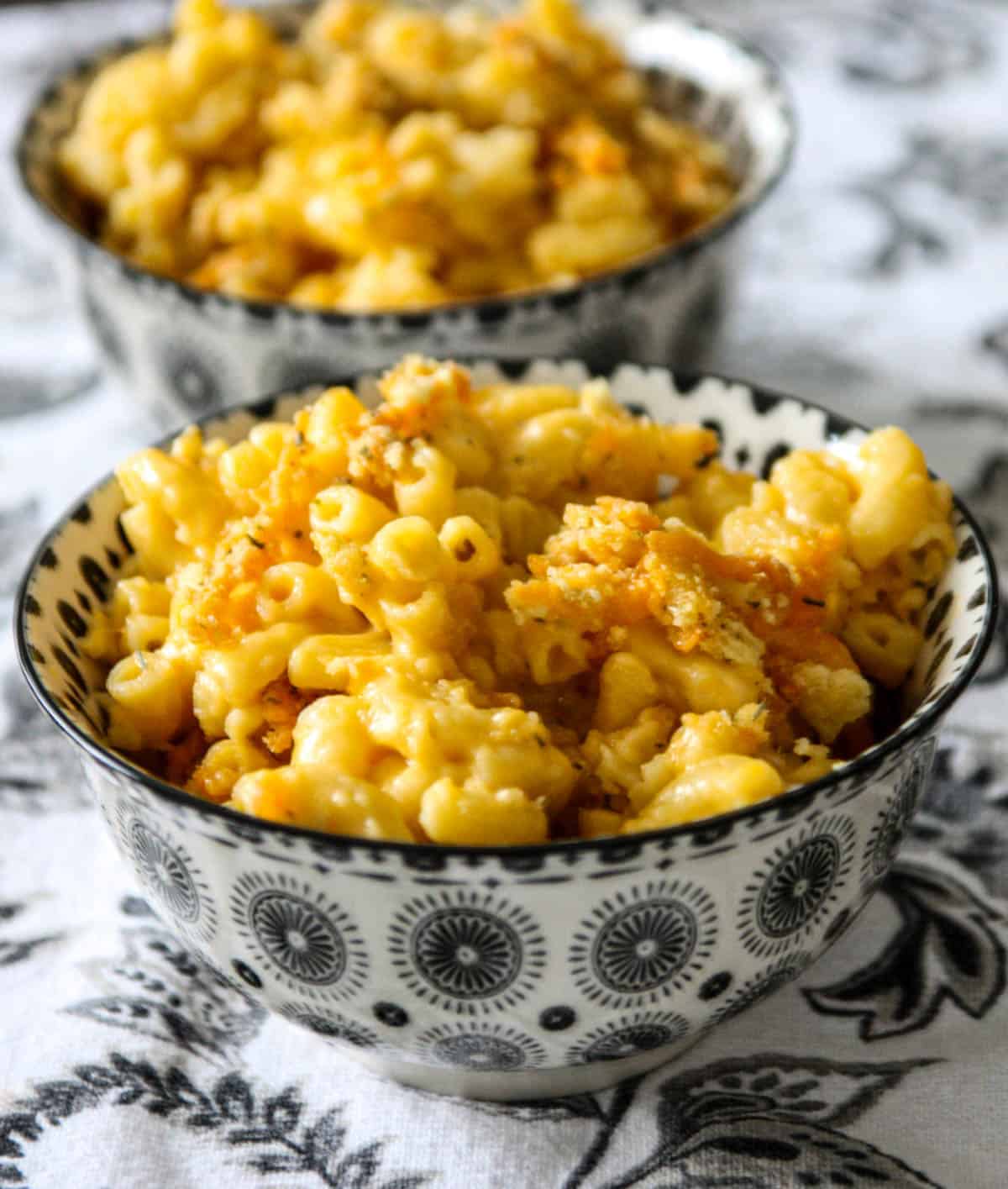 Old fashioned baked macaroni and cheese in two black and white bowls.