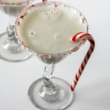 Candy cane martini in a martini glass, garnished with a candy cane.