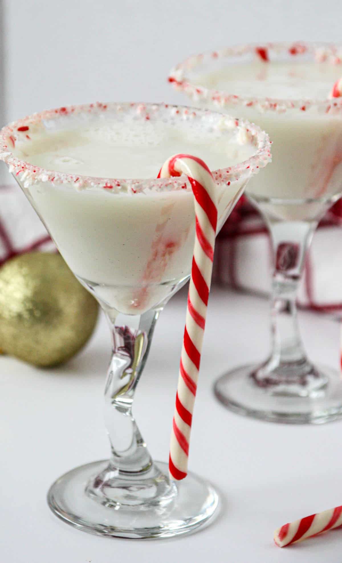 Candy cane martini drinks in two martini glasses garnished with candy canes.