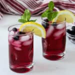 Two glasses of blueberry iced tea, garnished with lemon slices.