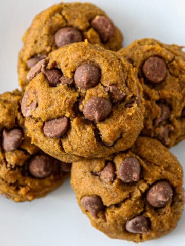 Five gluten free pumpkin cookies on a white plate.